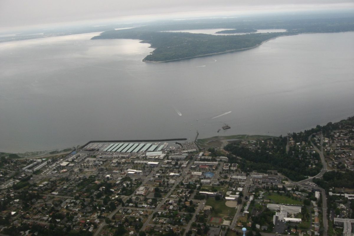 Aerial view of Des Moines, Washington, with its marina and breakwater on Puget Sound and Maury and Vashon Island across the gray water
