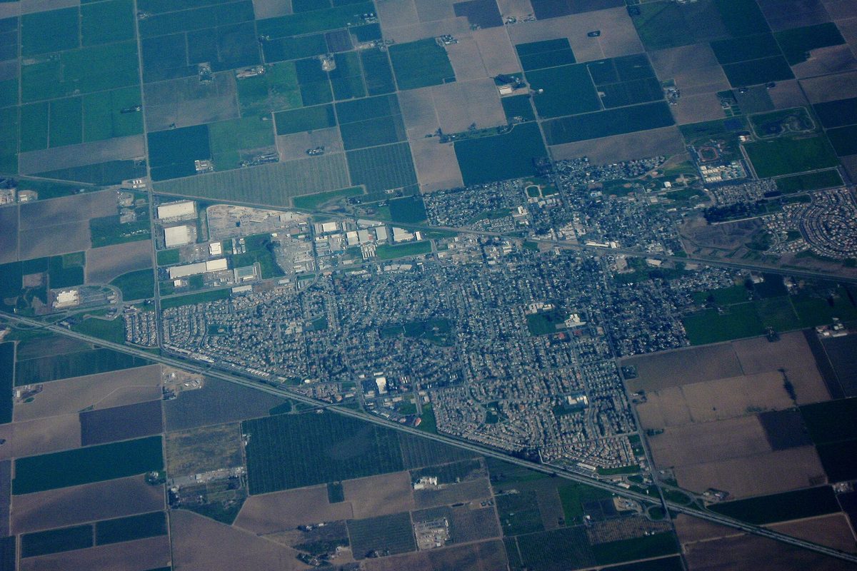 Aerial view of Dixon, a compact town of streets and rooftops with a highway along one side, surrounded by a patchwork of farm fields