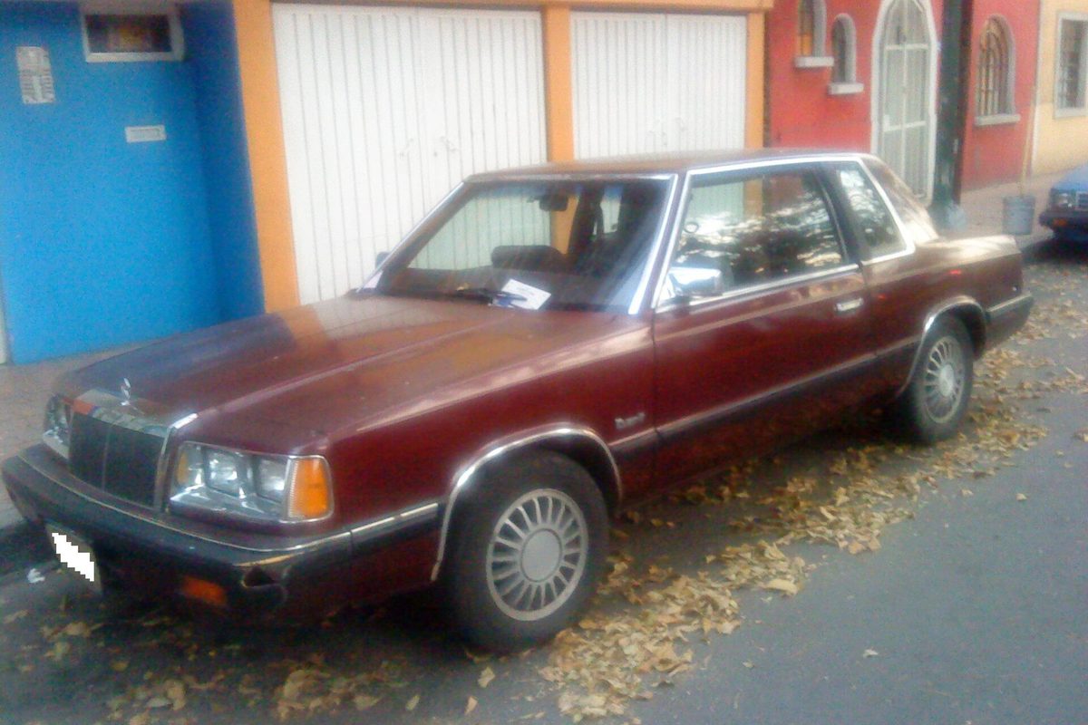 A maroon 1988 Dart K by Chrysler, a two-door sedan sold in Mexico, parked on a Mexico City street in fallen leaves