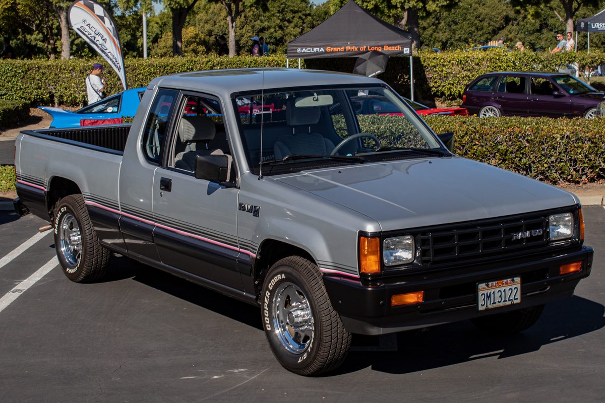A silver 1988 Dodge Ram 50 Sport extended-cab pickup with black lower trim and chrome wheels, parked at an outdoor car show