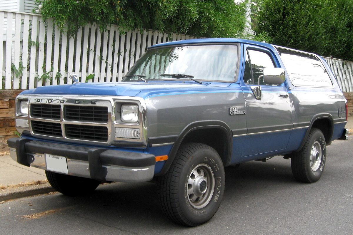 A blue and gray two-tone Dodge Ramcharger full-size SUV parked by a white picket fence