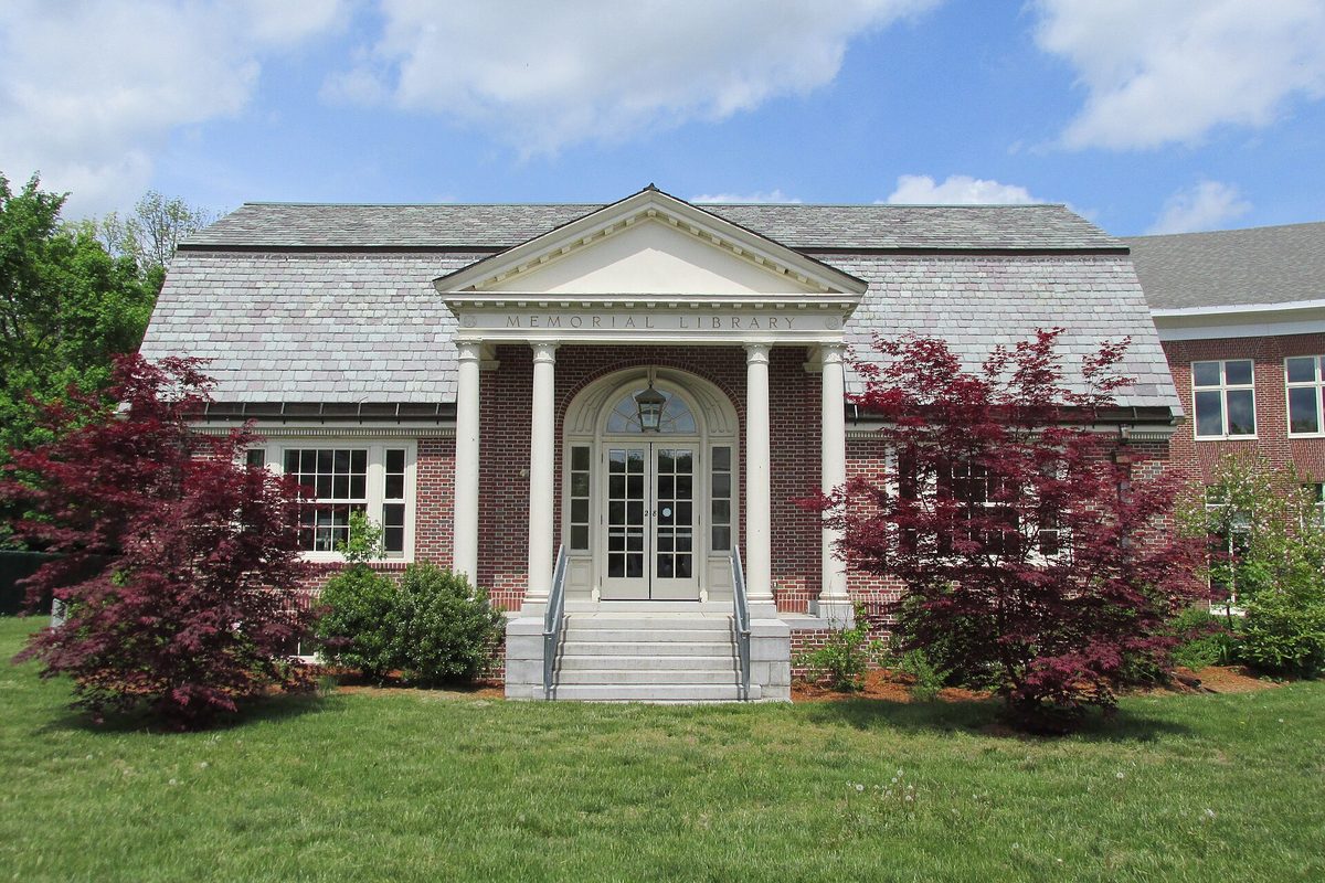 Parker Memorial Library in Dracut, a brick building with a slate roof, white columns and an arched glass doorway, framed by two red Japanese maples