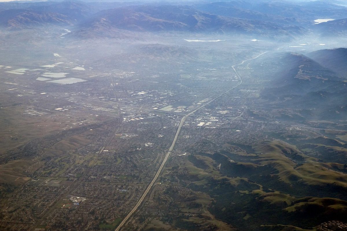 Fog lying over the hills around Dublin and Pleasanton in December, seen from the air, with a freeway cutting straight across the valley