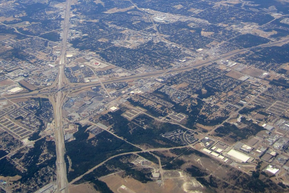 An aerial view over Duncanville showing a large highway interchange, neighborhoods of houses and trees, and flat commercial buildings