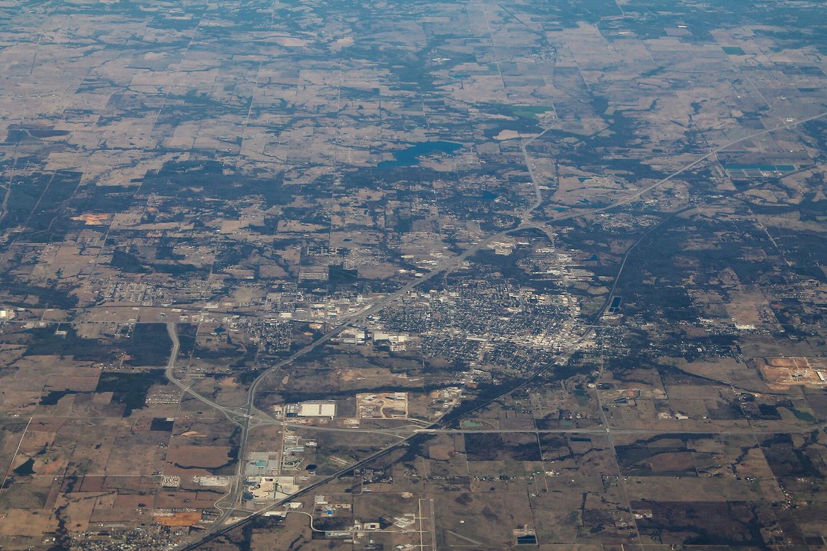 An aerial view of Durant spread among brown farm fields and woods, with highways curving past the town's grid of streets