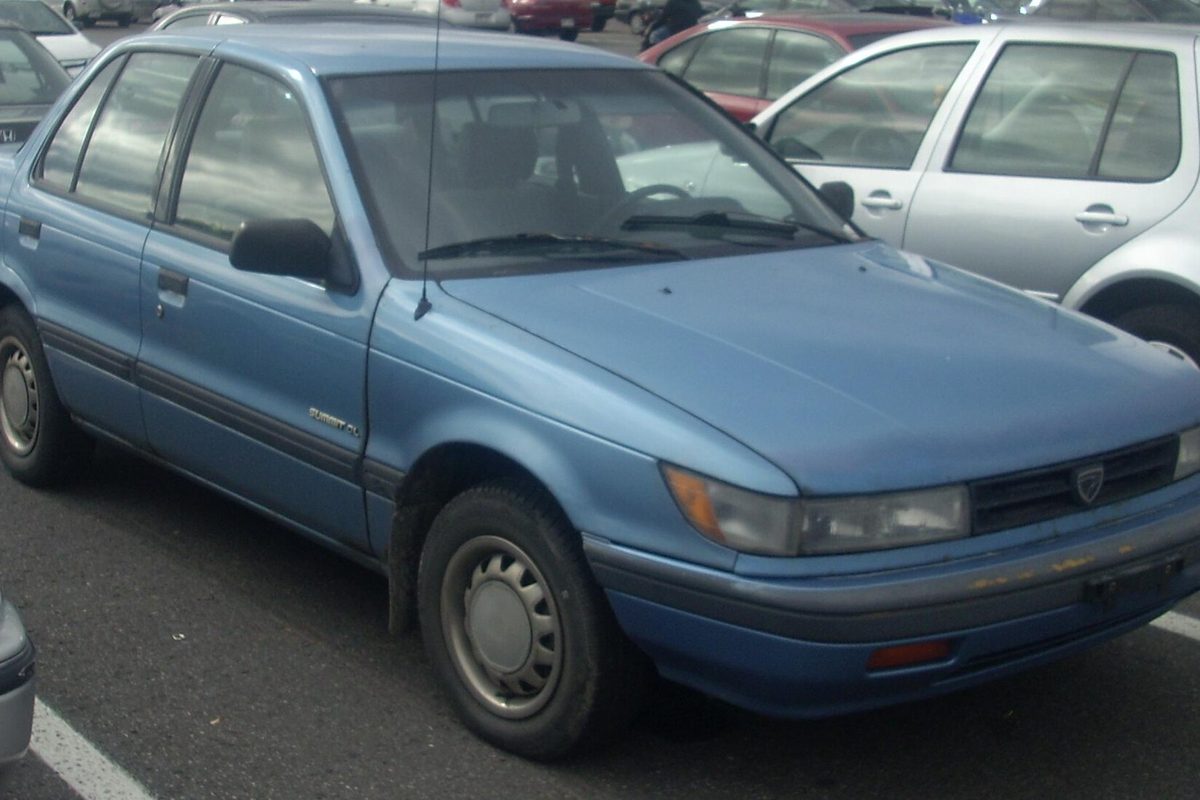 A light blue Eagle Summit sedan with plain steel wheels in a parking lot