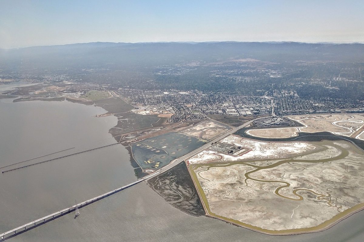 Aerial view of East Palo Alto beside San Francisco Bay, with the Dumbarton Bridge crossing the water and salt marshes in the foreground