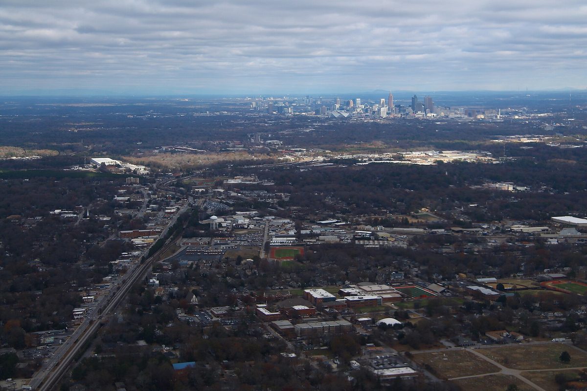 South side neighborhoods, US 29 and the rail line seen from a plane after takeoff, running north toward the Atlanta skyline under gray clouds