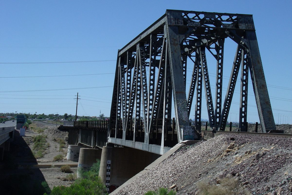 The 1895 Santa Fe Railroad steel truss bridge over the Agua Fria River in El Mirage under a clear blue sky