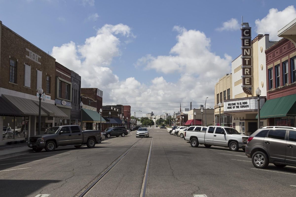 Downtown El Reno looking south on Bickford Avenue, pickups parked by brick storefronts, the vertical Centre theater sign and a streetcar track in the road