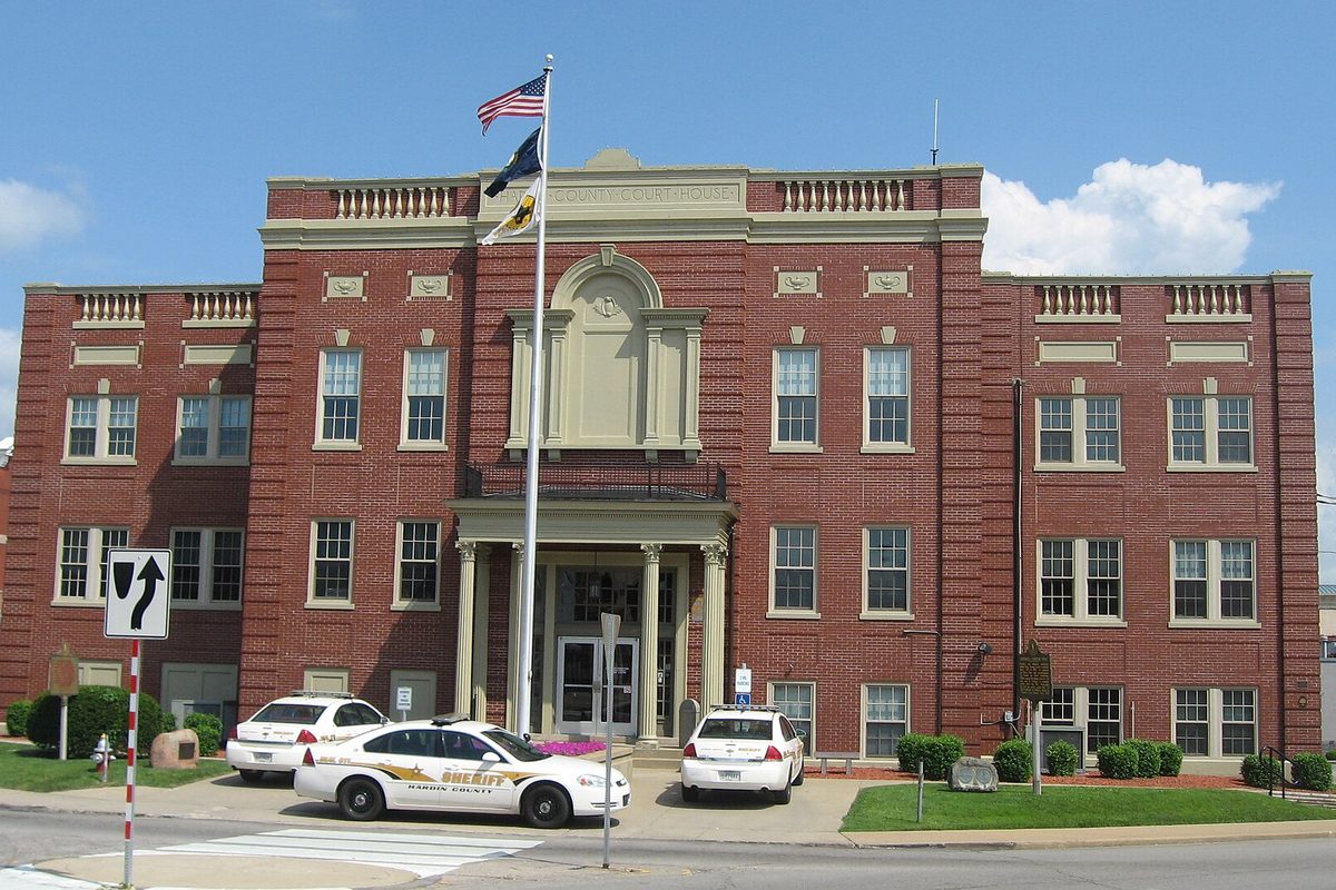 The west front of the red brick Hardin County Courthouse on Courthouse Square in Elizabethtown, with flags and sheriff's cruisers parked out front