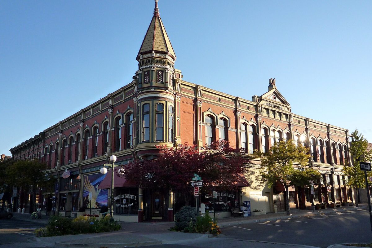 The red brick Davidson Building in downtown Ellensburg, with its corner turret and arched windows, under a clear blue sky