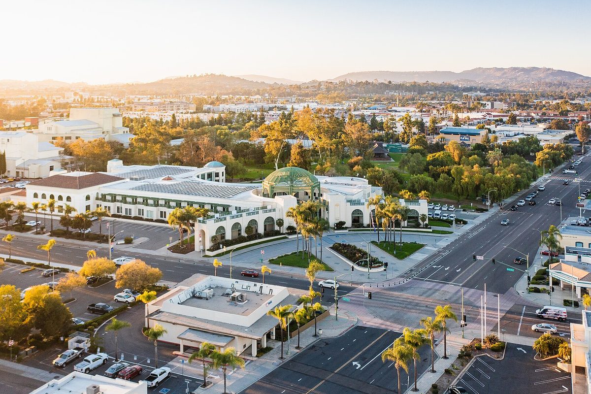 Sunset aerial view of Escondido City Hall, a white building with a green dome, at Broadway and East Valley Parkway, with trees and hills behind