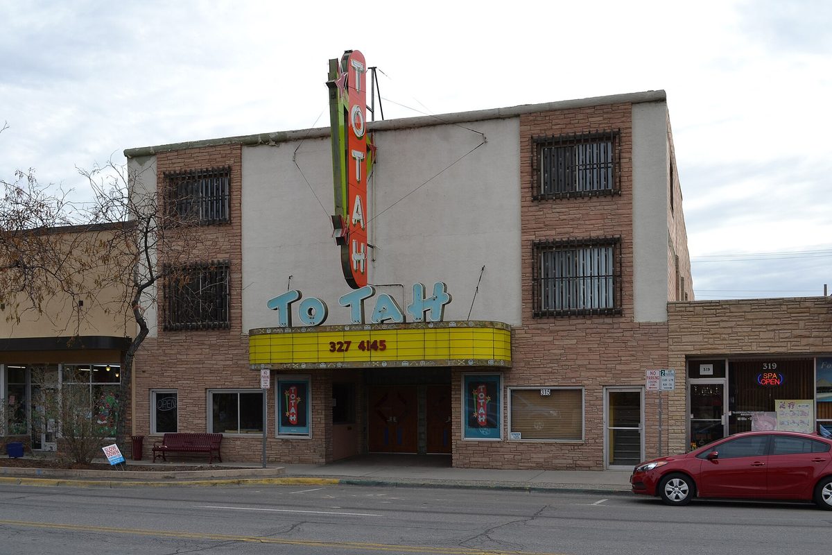 The Totah Theater on a Farmington street, with its tall red neon sign, a yellow marquee and a red car parked out front