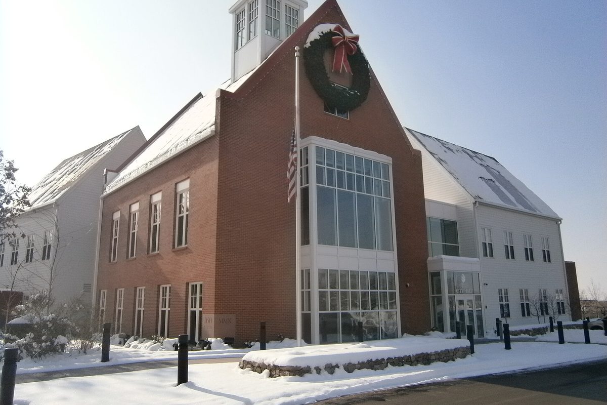 Farmington's brick city hall with a white cupola and a wreath above its tall glass entry, snow on the roofs and the ground