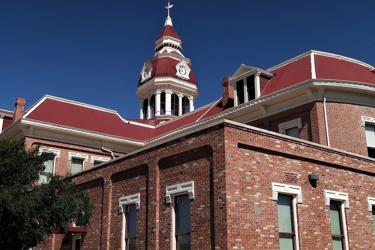 Florence's historic red brick courthouse with a white clock tower and red roof against a deep blue sky