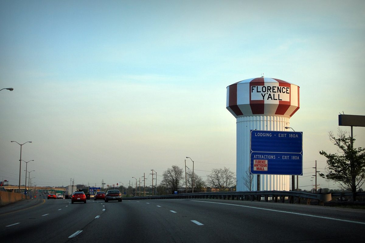 The red and white striped Florence Y'all water tower beside the interstate, with blue exit 180A signs for lodging and attractions
