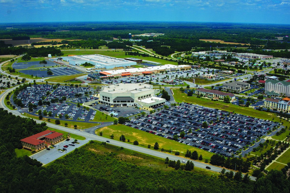 Aerial view of western Florence, with large commercial buildings, wide parking lots full of cars, curving roads and green fields stretching to the horizon
