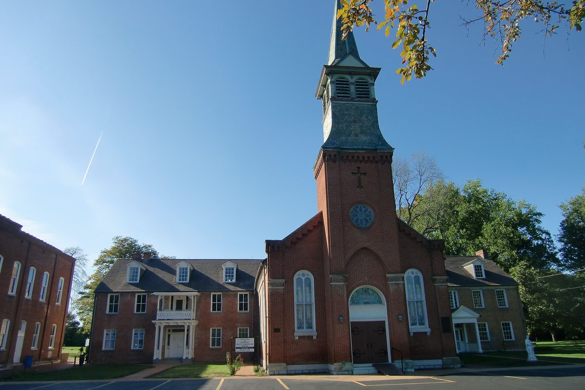 St. Ferdinand's Shrine in Florissant, a red-brick church with a tall green-and-slate steeple, its brick convent building beside it