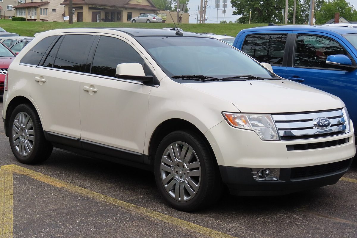 A pearl white 2008 Ford Edge Limited with chrome wheels, parked in a lot next to a blue pickup truck