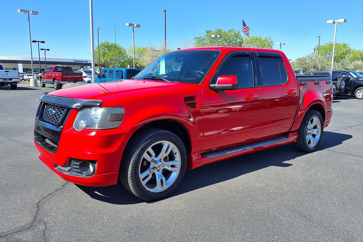 A red 2008 Ford Explorer Sport Trac Adrenalin four-door pickup with chrome wheels on a sunny dealer lot