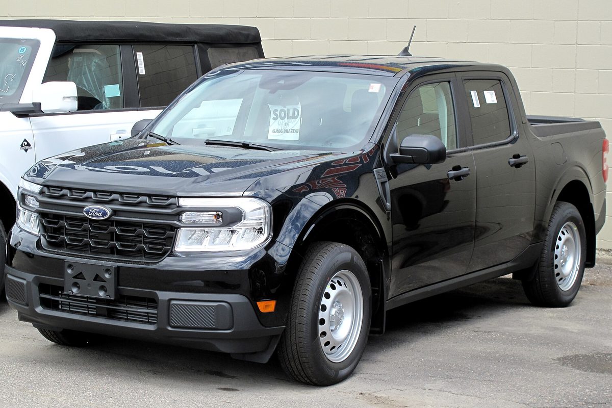 A black 2022 Ford Maverick XL crew cab pickup with steel wheels and a SOLD sign on the windshield, parked on a dealer lot