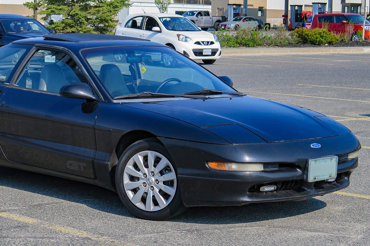 A black 1993 Ford Probe GT coupe parked in a lot, seen from the front right