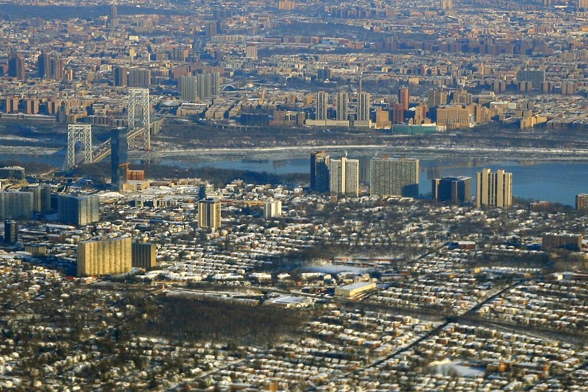 Aerial view of Fort Lee's high-rise towers and snow-dusted rooftops, with the George Washington Bridge and the Hudson River leading to Upper Manhattan