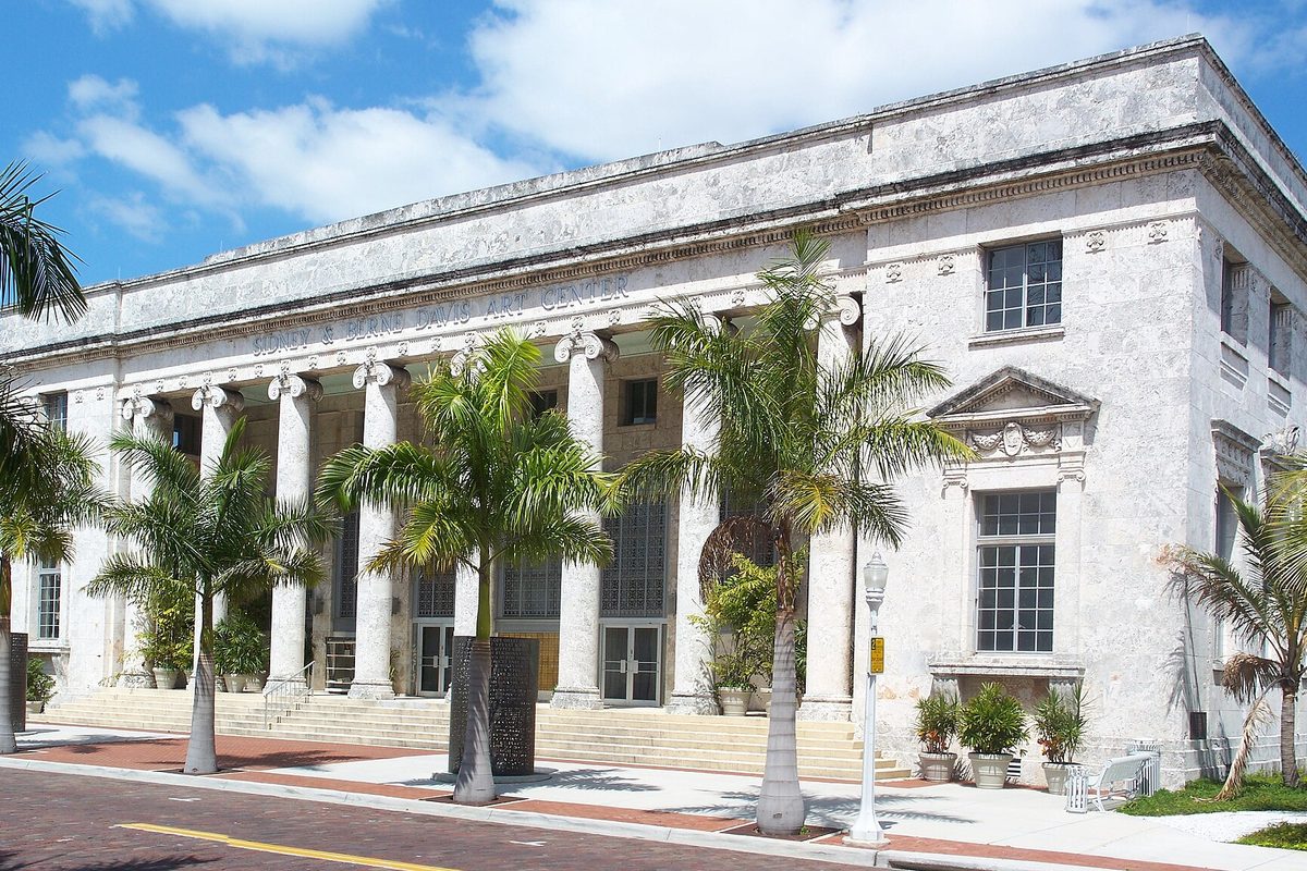 The white columned 1933 former courthouse in downtown Fort Myers, now an arts center, with palm trees along a red brick street