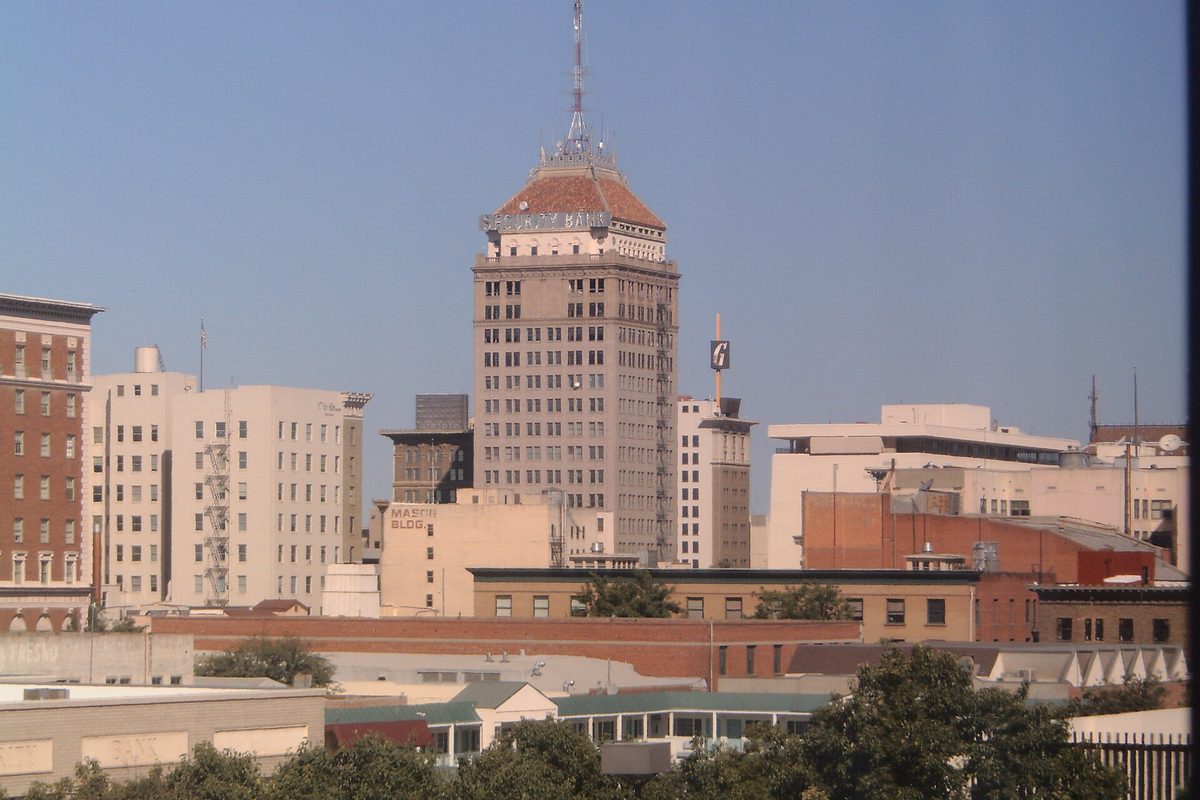 Downtown Fresno skyline with a tall office tower topped by a red-tiled dome and spire, rising above older brick and concrete buildings