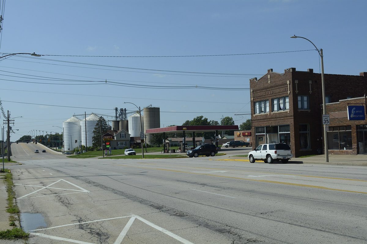 Looking west along Main Street in Galesburg, a wide road past a gas station, grain bins and a two-story brick building
