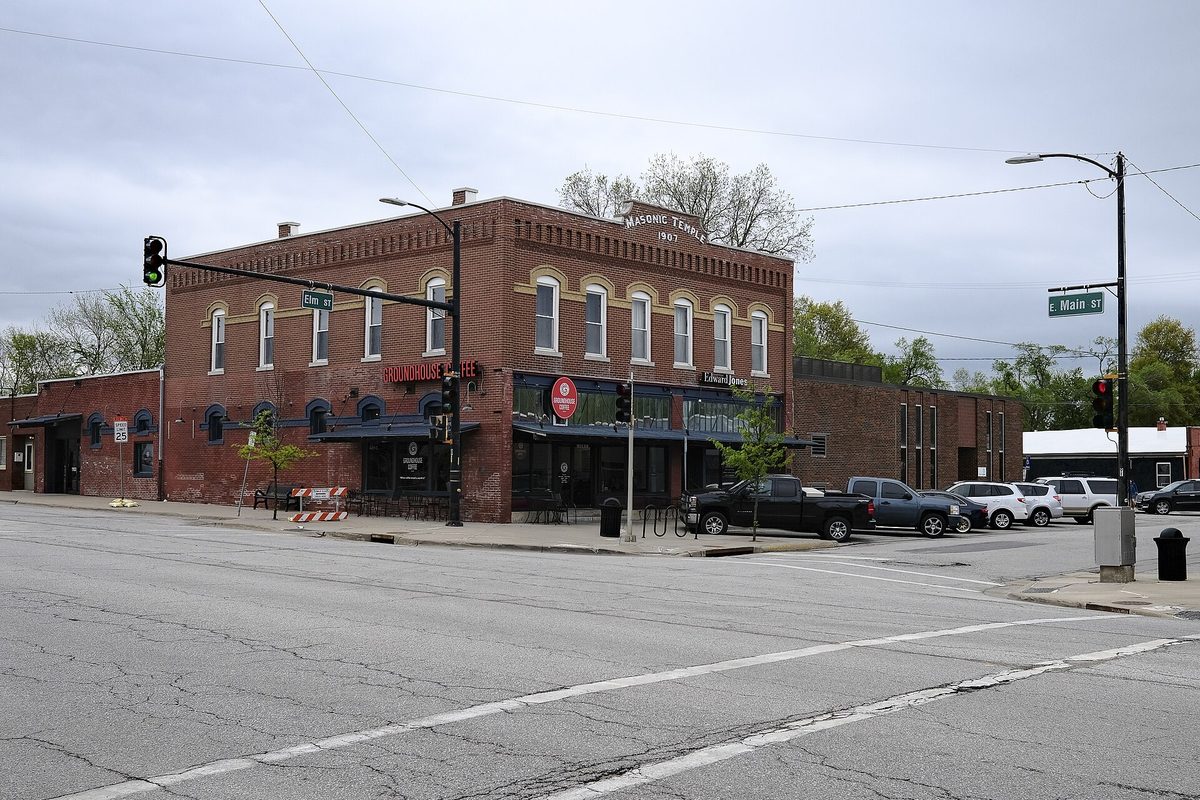 A two-story red brick Masonic Temple building at the corner of Main and Elm in Gardner, with pickup trucks parked in front