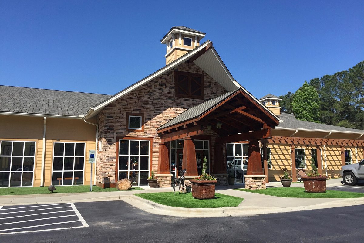 The stone and timber entrance of Carolina Ranch Animal Hospital in Garner, with a cupola, planters and an empty parking lot under a deep blue sky