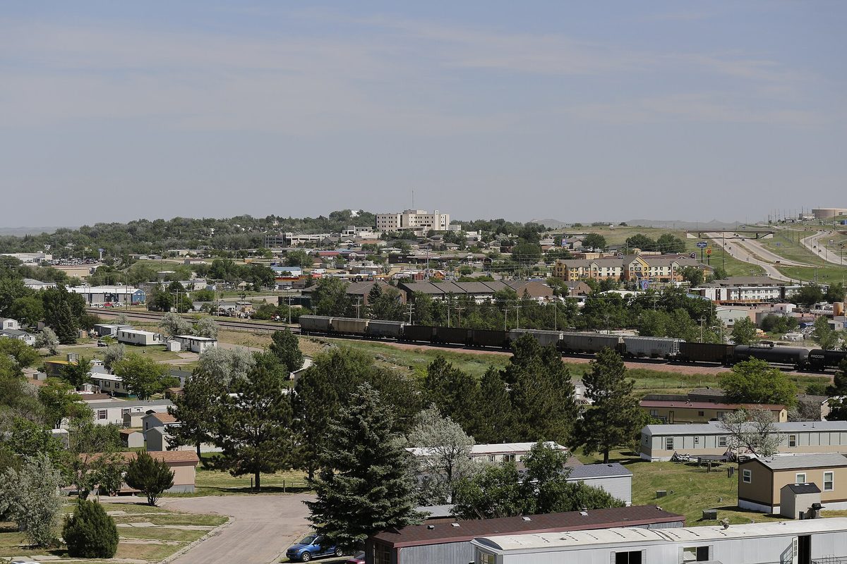 Gillette seen from Overlook Park: rows of houses and trees, with a long freight train crossing the middle of town under a pale sky