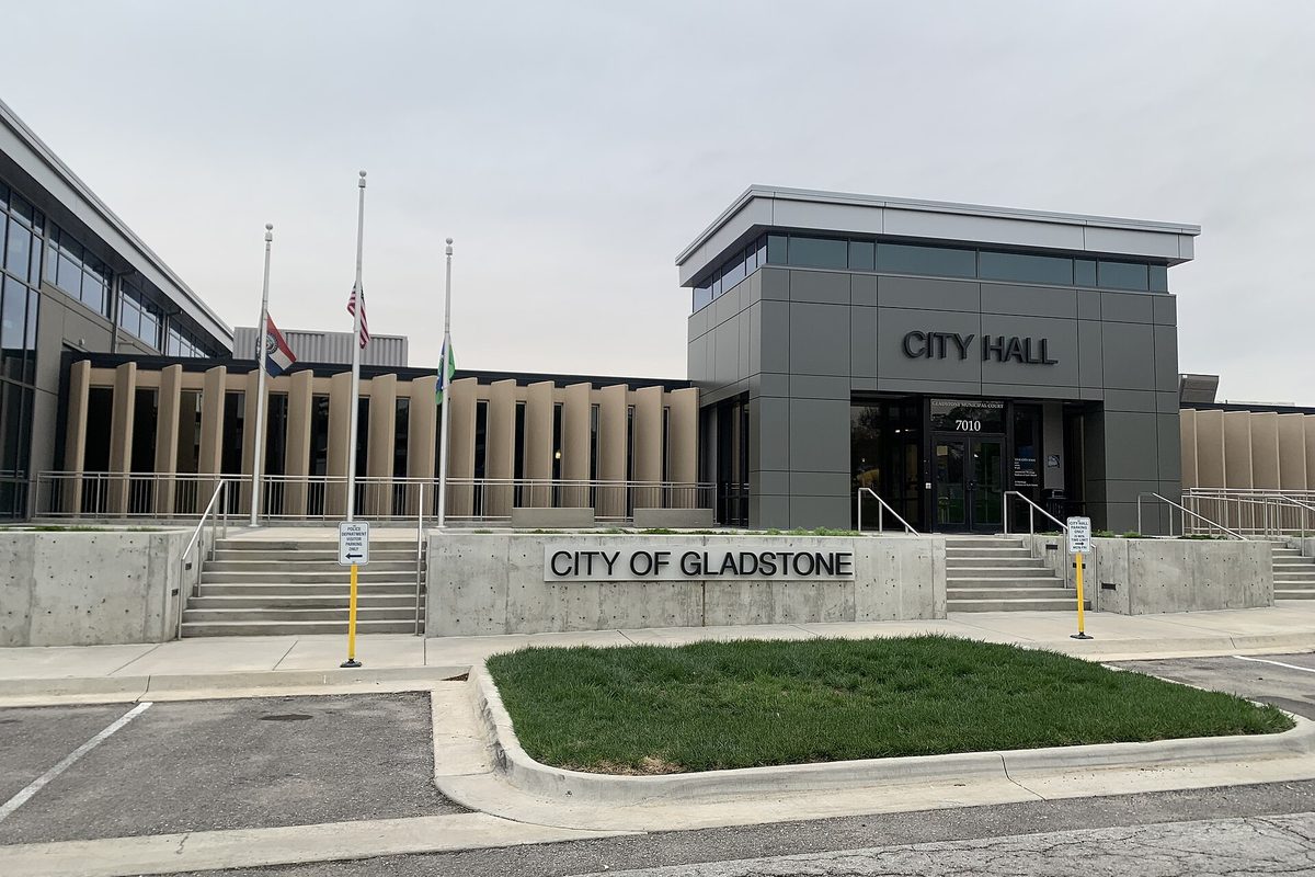 Gladstone City Hall, a gray modern building with a CITY HALL sign over the doors, flags out front and a lettered City of Gladstone wall beside the steps