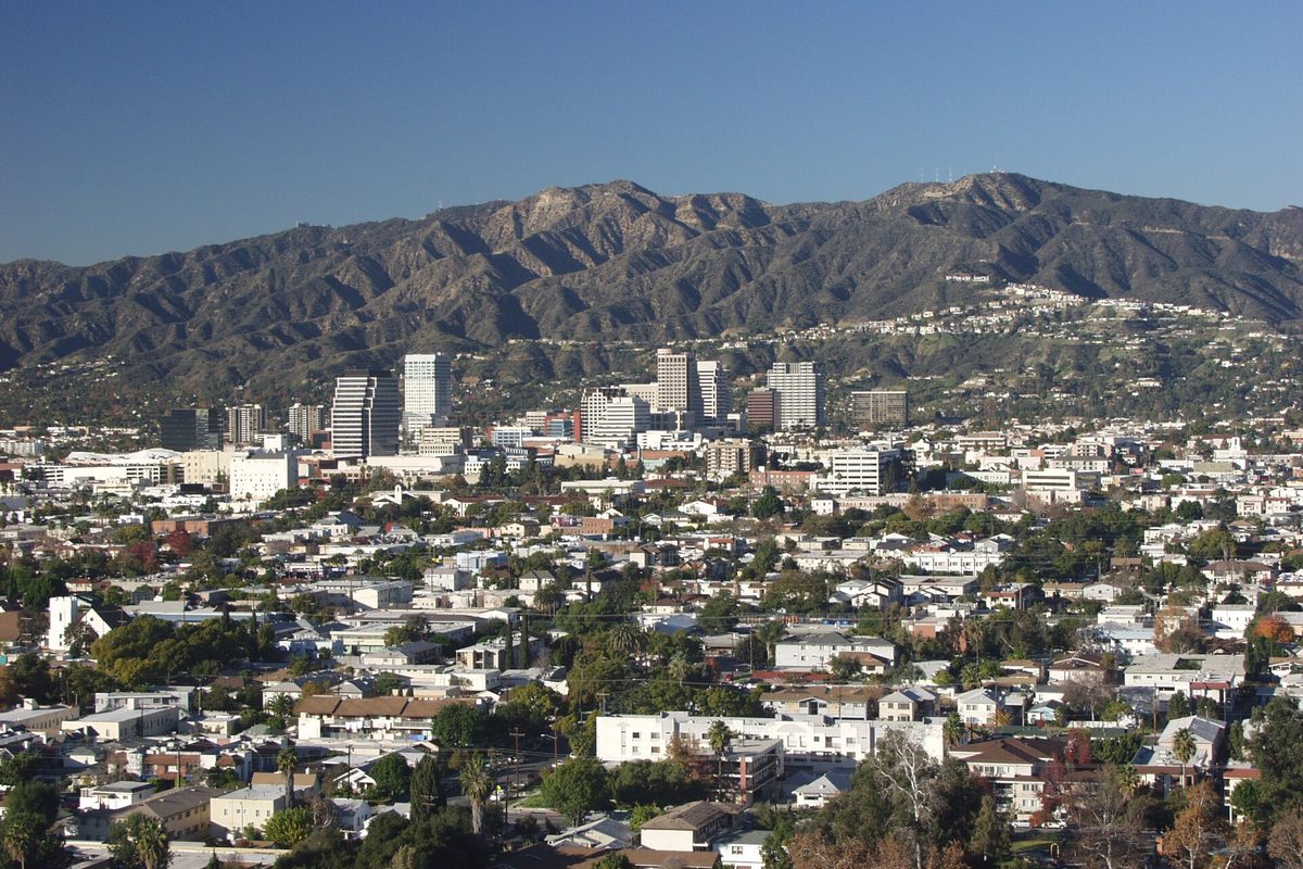 Downtown Glendale's office towers and the surrounding neighborhoods of houses and trees, with a ridge of brown mountains behind under a clear sky