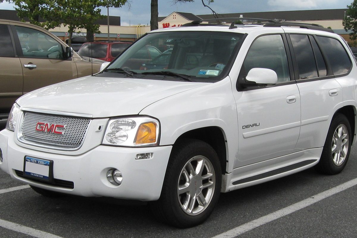 A white GMC Envoy Denali SUV parked in a shopping-center lot, seen from the front corner