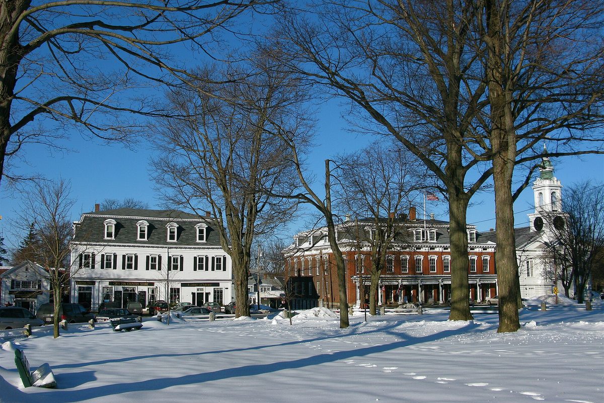 Grafton Common under deep snow, with bare trees, a white three-story building, a red brick inn with columns and a white church steeple