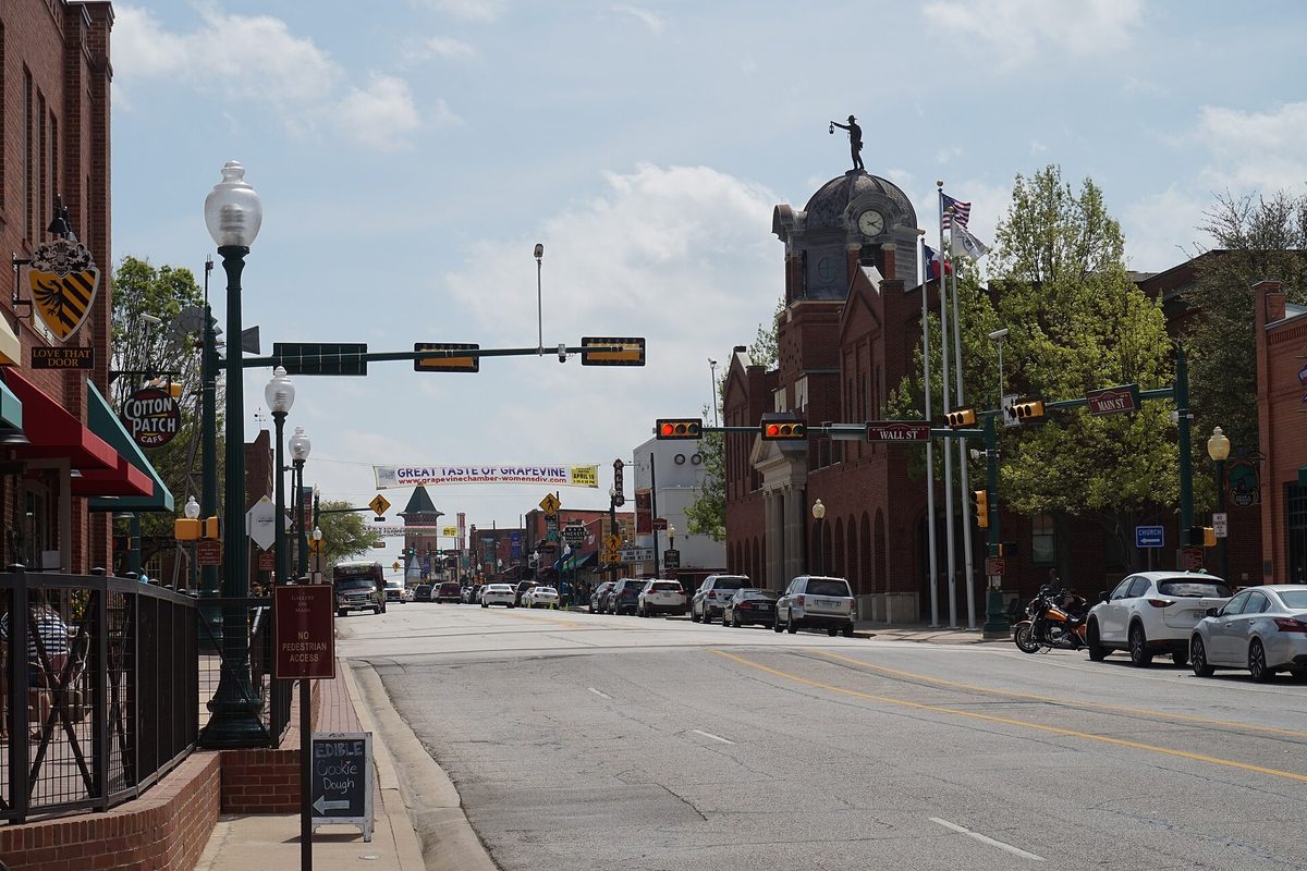 Main Street in downtown Grapevine, with brick storefronts, traffic signals over the road and a domed clock tower topped by a statue
