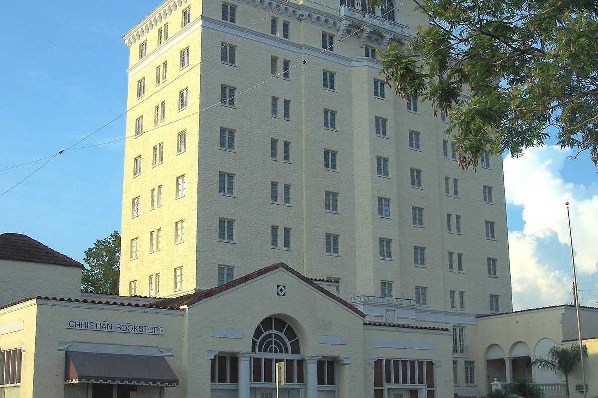 The tall cream-colored former Polk Hotel tower in Haines City, rising behind a low tile-roofed building with a Christian Bookstore sign