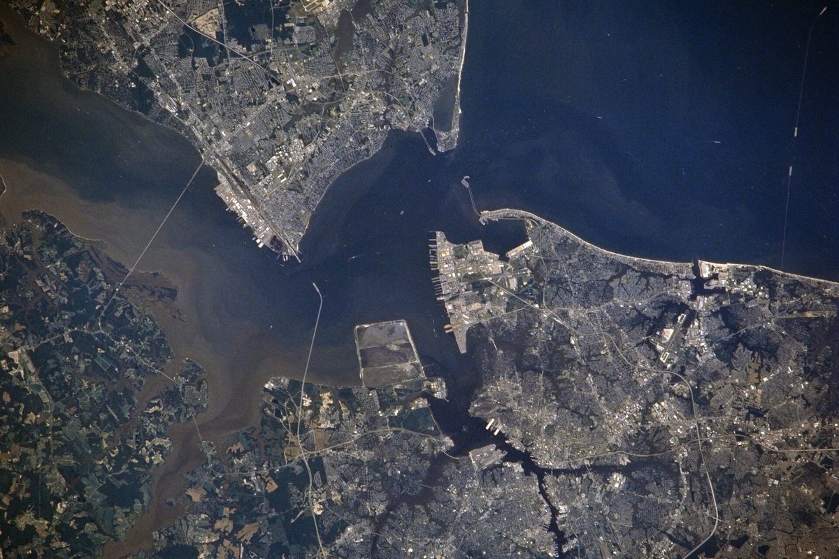 Hampton Roads photographed from orbit, with the Newport News peninsula at upper left, the harbor in the middle and city streets spreading along the shorelines