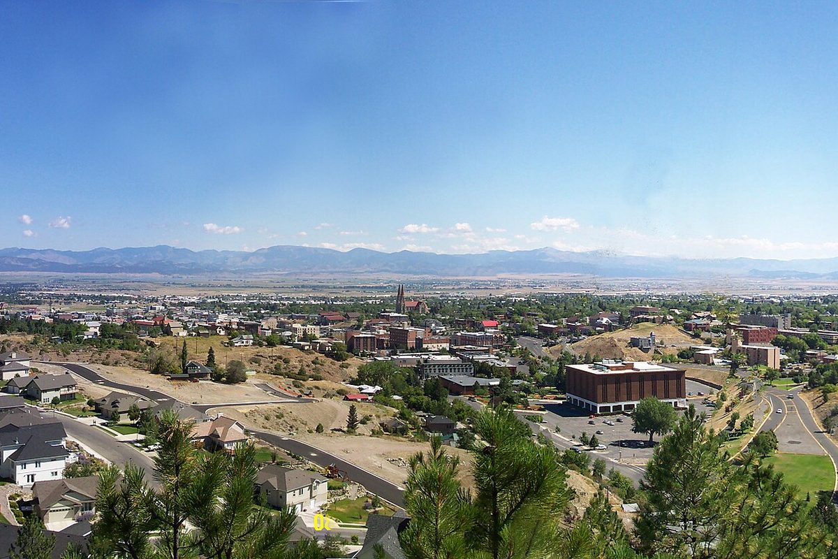 Helena seen from a pine-covered hillside, with new houses in the foreground, cathedral spires and brick buildings in the middle and a wide valley and distant mountains beyond
