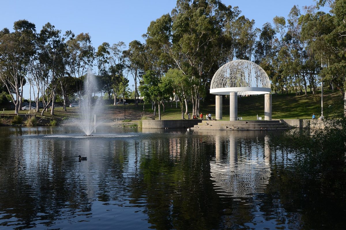 A pond with a fountain and a white domed gazebo among eucalyptus trees in Refugio Valley Park, Hercules