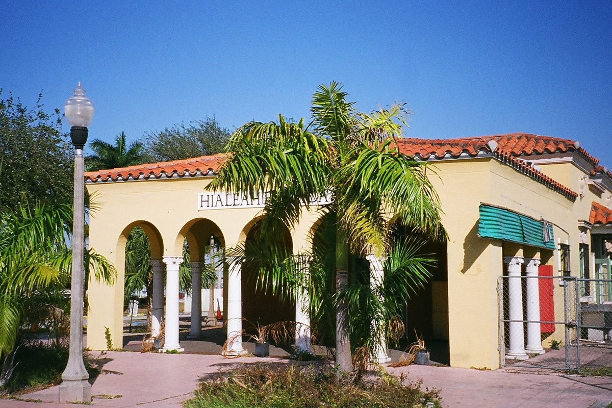 Hialeah's old Seaboard Air Line train station, a cream stucco building with arches, white columns, a red tile roof and palm trees in front
