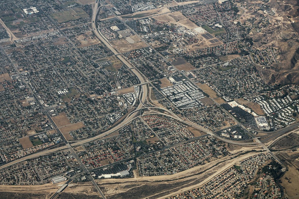 Aerial view of the CA-210 and CA-330 freeway interchange in Highland, surrounded by grids of houses and dry hills to the east