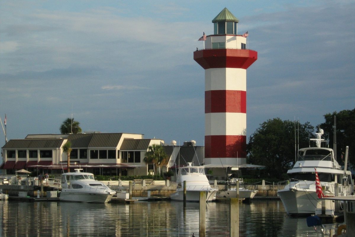 The red and white striped lighthouse at Harbour Town on Hilton Head Island, rising over a marina of white boats and low waterfront buildings