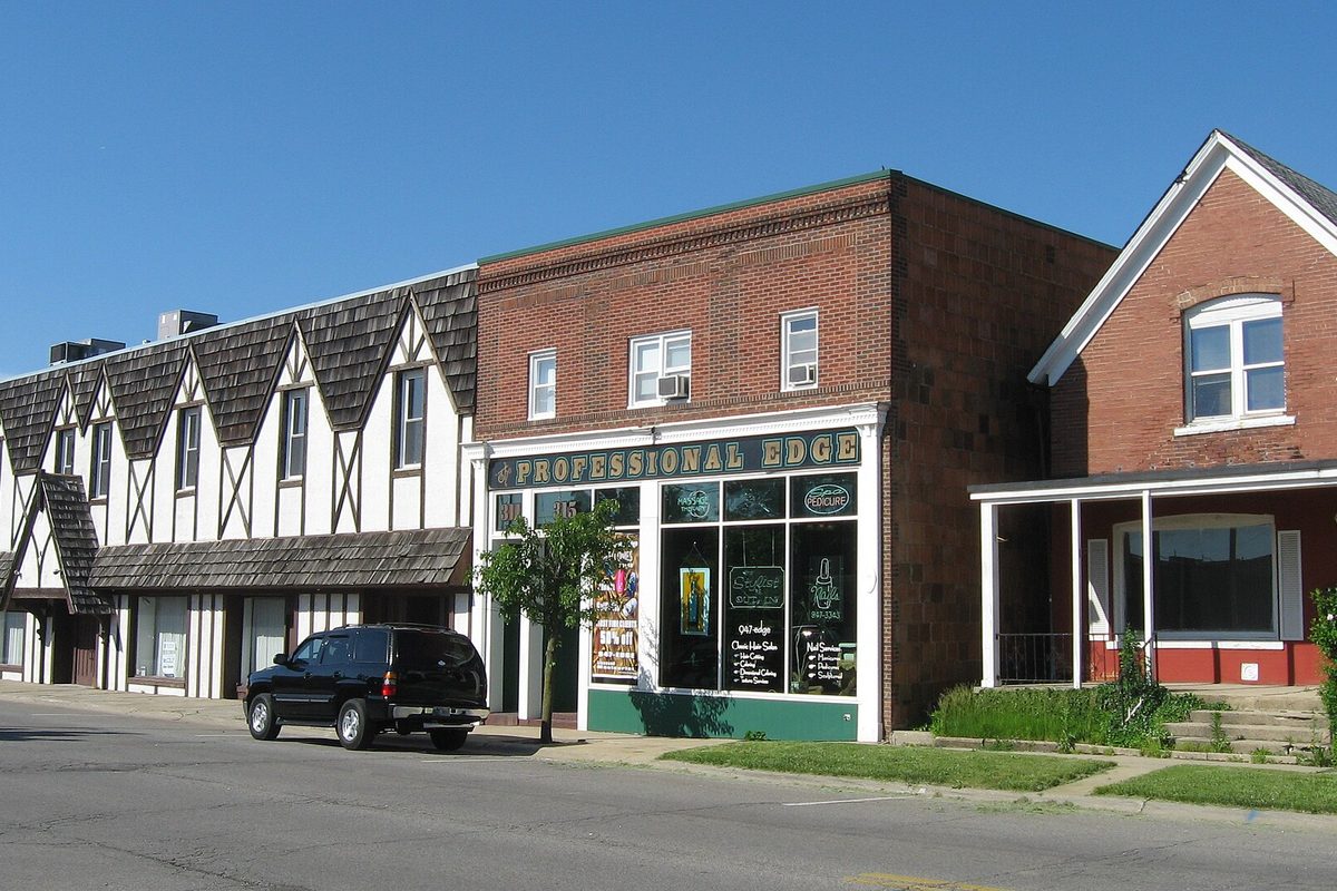 Brick and half-timbered storefronts on Center Street in Hobart, with a black SUV parked at the curb under a clear blue sky