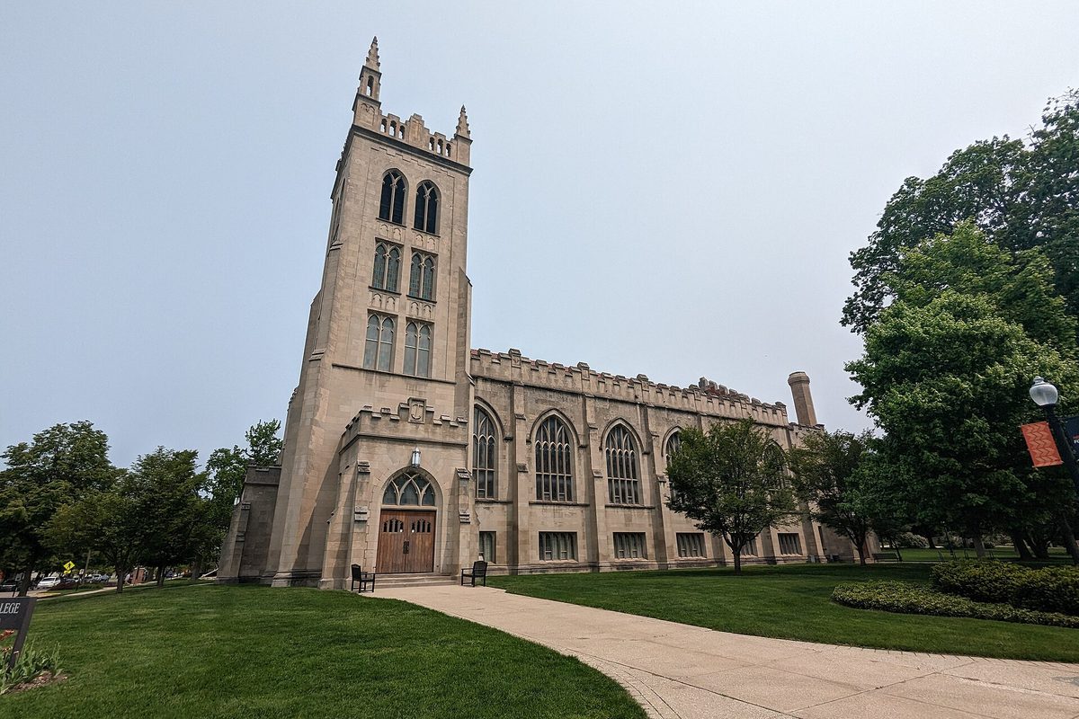 Dimnent Memorial Chapel at Hope College in Holland, a tall stone Gothic church with a square bell tower, seen across a lawn under a pale sky