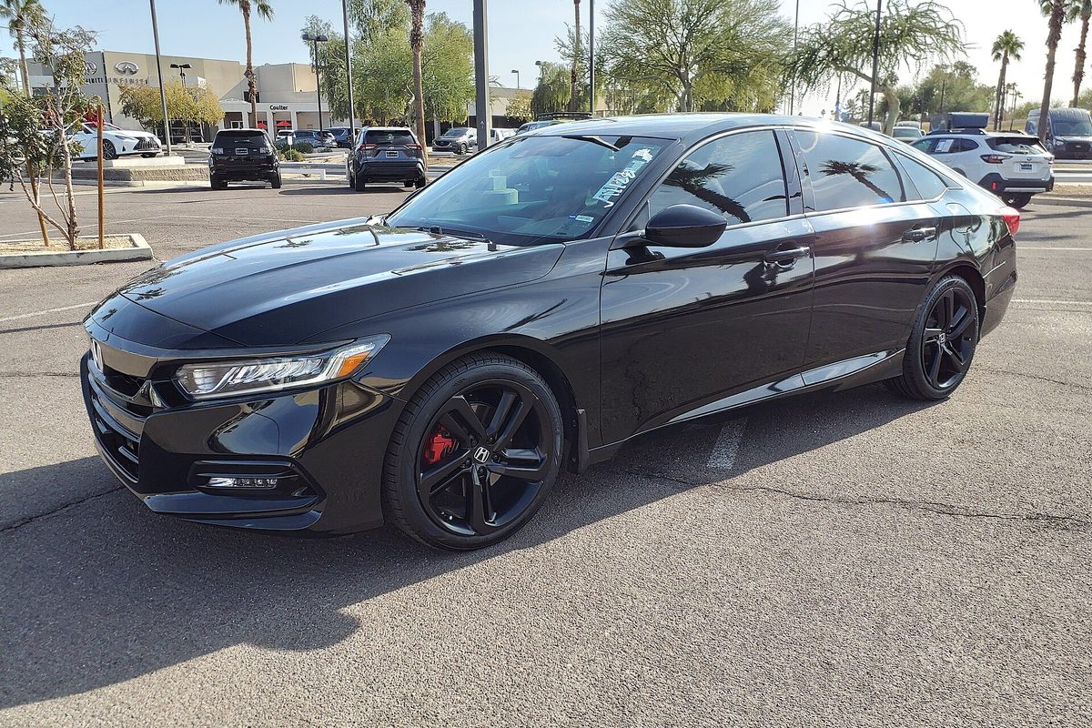 A black Honda Accord Sport sedan of the 2018-2022 generation, with black wheels and red brake calipers, parked on a sunny lot lined with palm trees in Mesa, Arizona