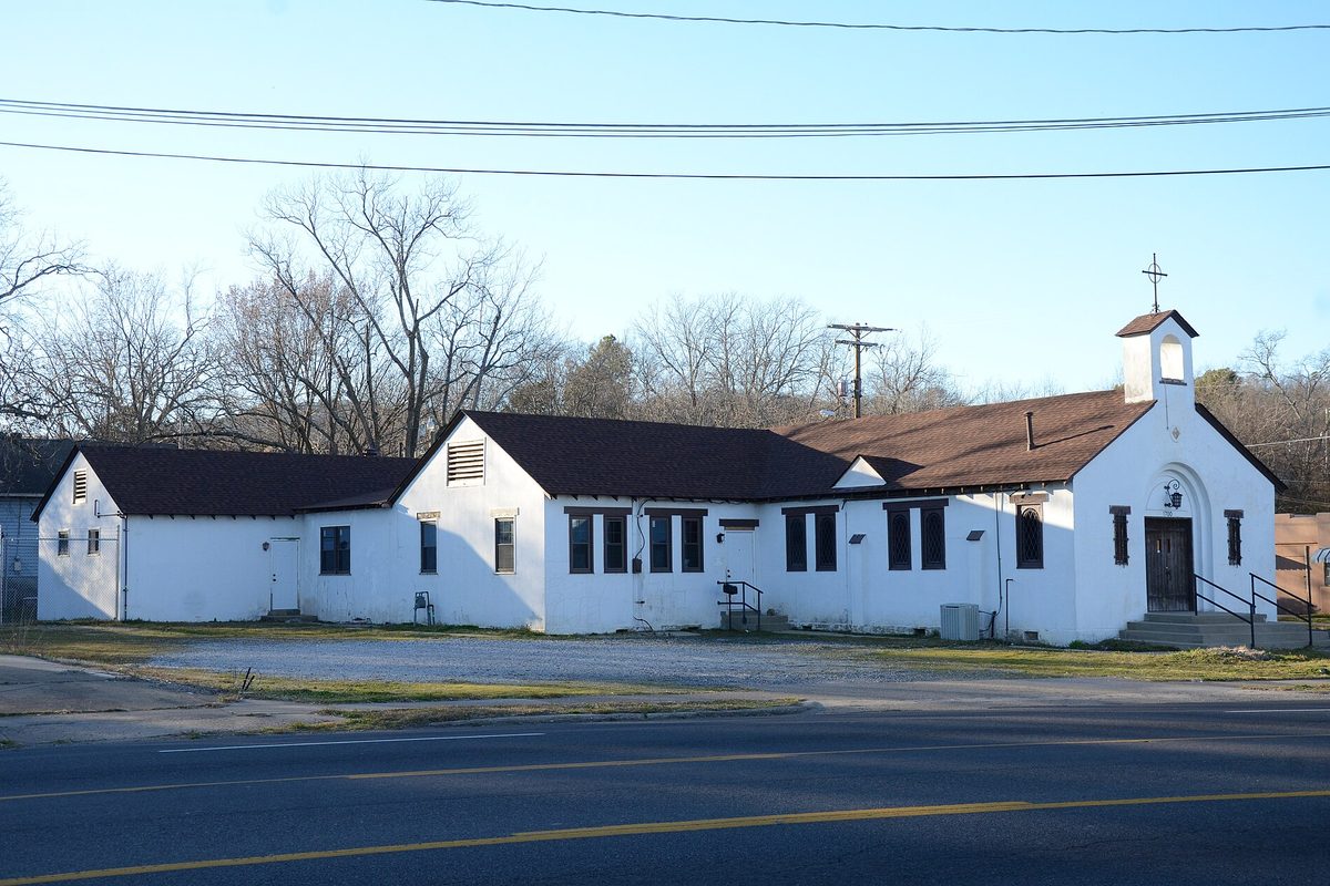 First Lutheran Church in Hot Springs, a long white building with a small bell tower and a cross, beside a road under bare winter trees
